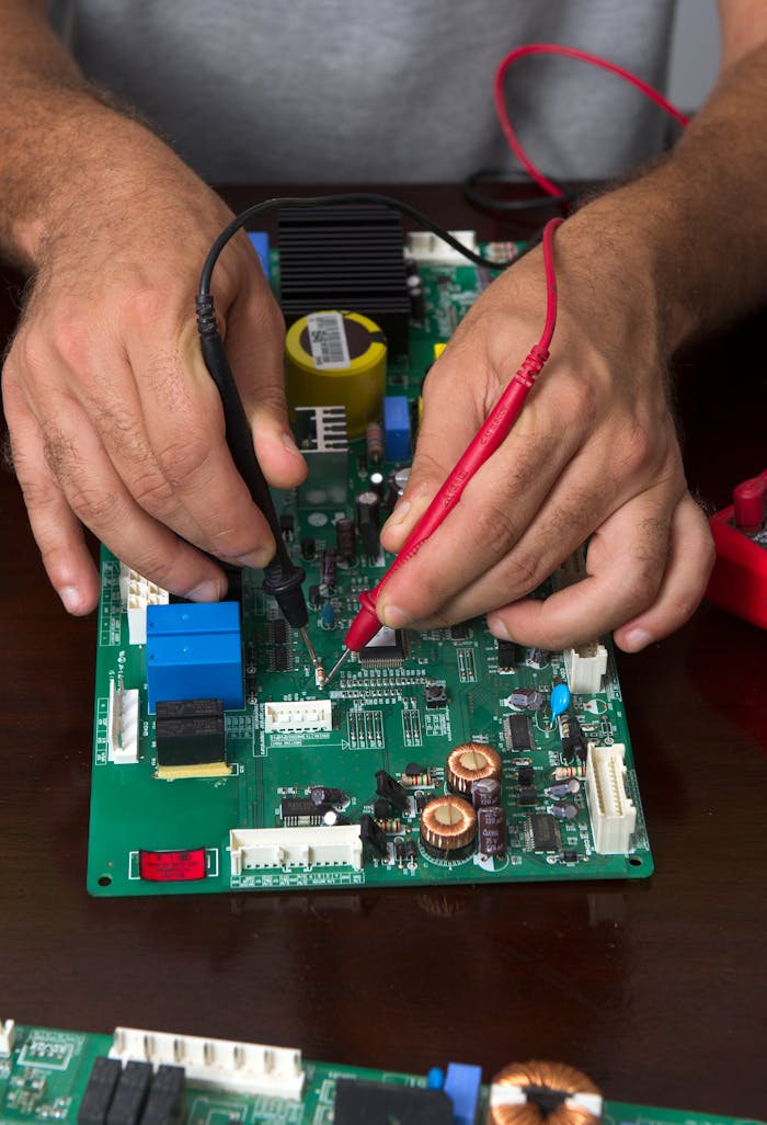 services-04 Close-up of hands using probes to test a circuit board during electronic repair.