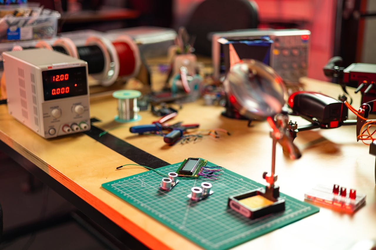 about-img A detailed view of an electronics workshop with various tools and components on a workbench.